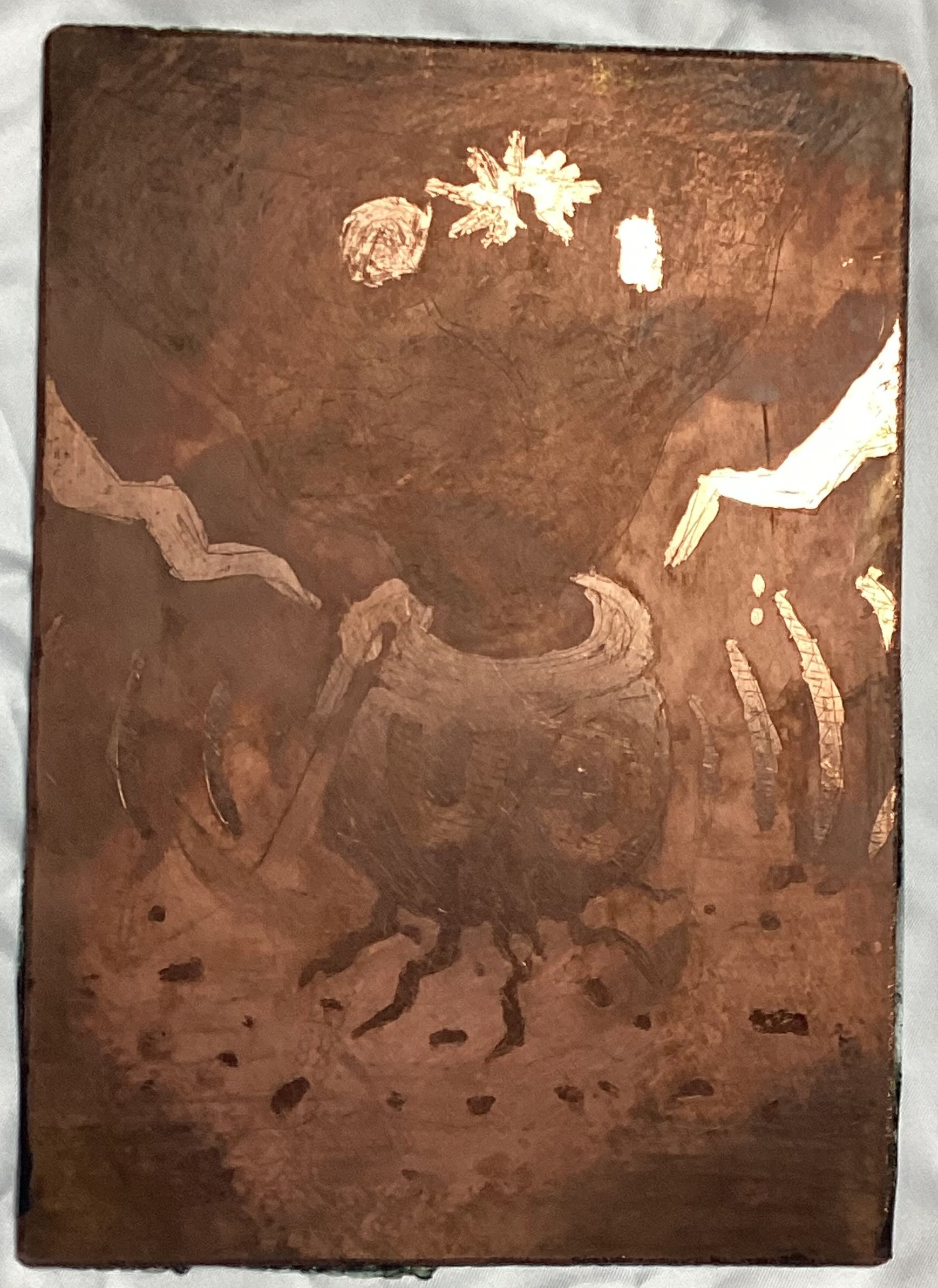 1: An image etched onto a plate of copper. Although hard to make out, it is supposed to be a cauldron with the letters CU emblazoned on it along with the number 29. Within the cauldron is a spool of wires wound around something containing bubbling molten metal releasing smoke. From this pool something that resembles a cross between a tree and wires is sprouting out, at the end of which are various forms of electronics. Leaning on the cauldron is a pickaxe and at the bottom of the cauldron there is a crack from which molten metal resembling the shape of roots leaks into the ground, or metal ore being sucked into the cauldron from the ore in the stratified ground. On either side of the cauldron there are waves resembling depictions of signals radiating outward. In the background there are poles holding up power cables.